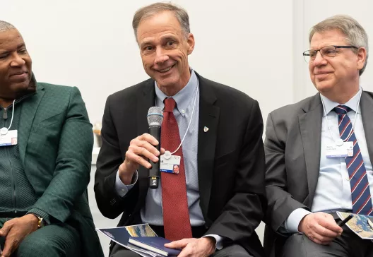 three men on panel at a talk.