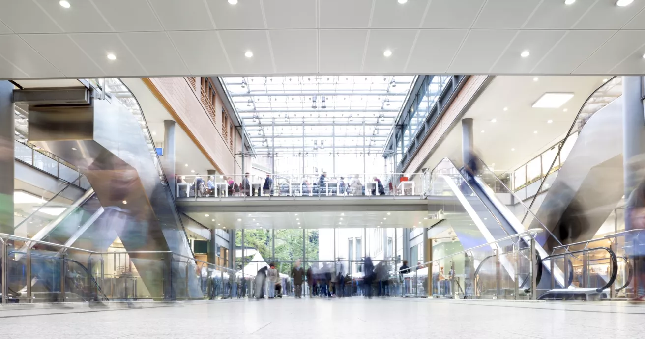 Large modern shopping mall with crowds of people walking.