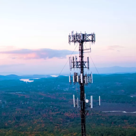 Cell towers on mountain peak with scenic valley view.