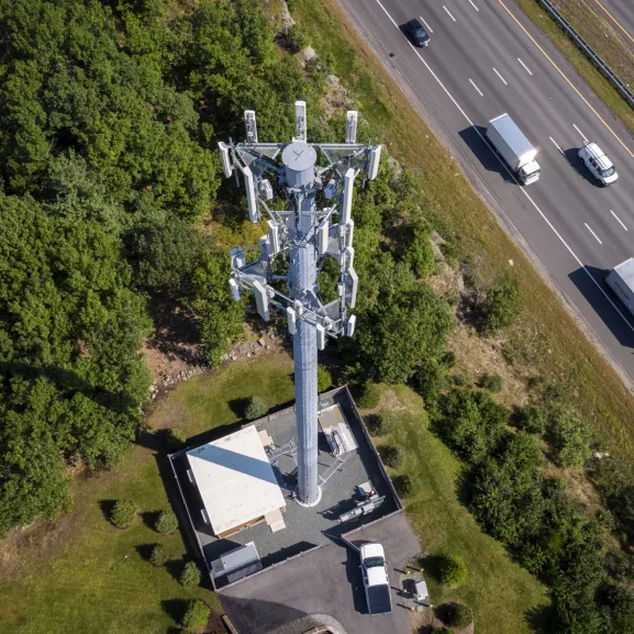 A cell tower stands by a highway, seen from above.