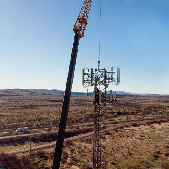 Cell tower in desert with crane.