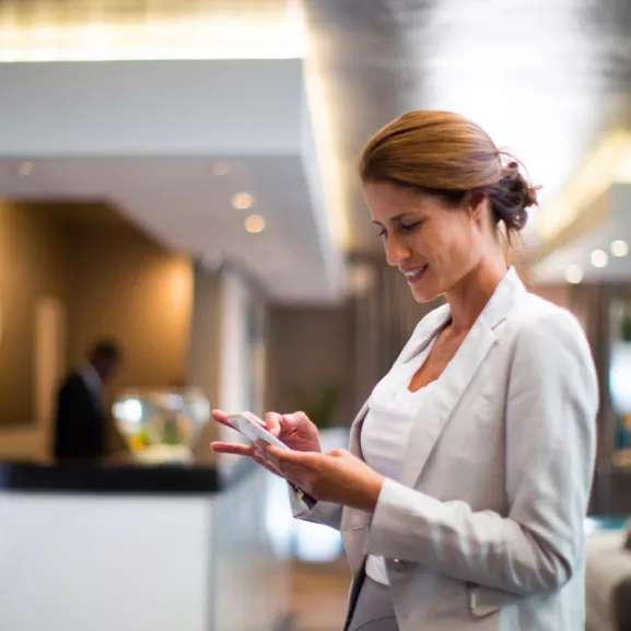 A woman in a business suit looking at her phone.