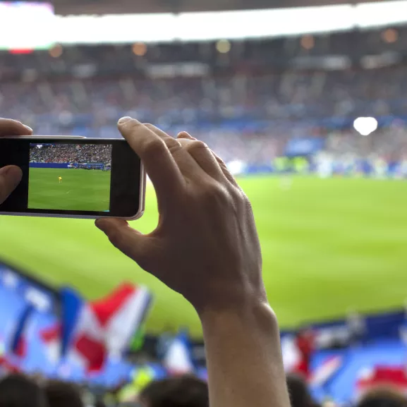 French football fan taking cell phone picture.