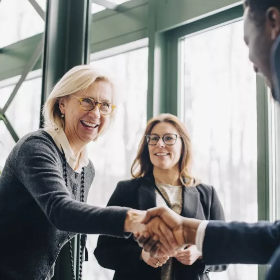 Senior businesswoman greeting colleagues during conference.