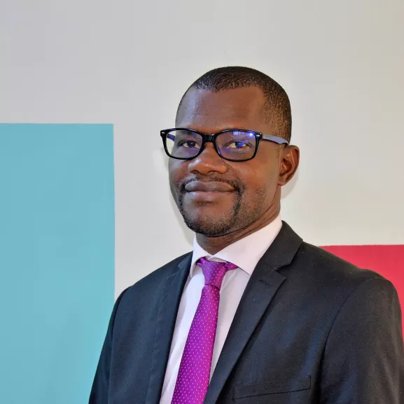 A man standing before a colorful wall.