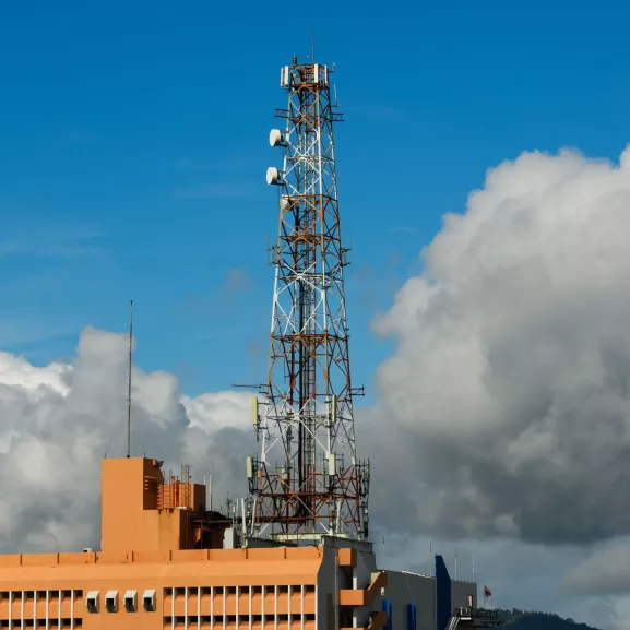 5G cellular communications tower over building in city.