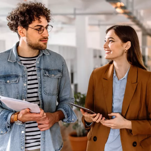 Man holding paper while looking at a woman holding a tablet