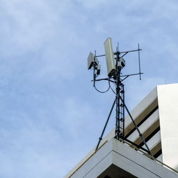 Antennas For Mobile Telephones On Roof Of Building Against Sky.