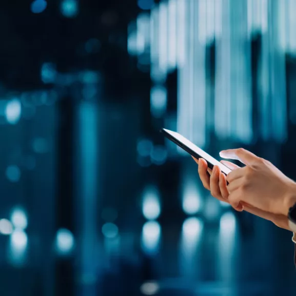 Cropped shot of young Asian woman using smartphone against futuristic background.