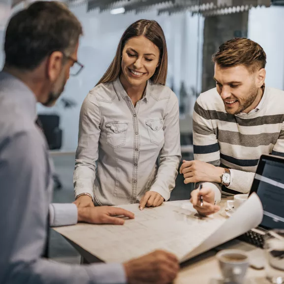 Young couple and their real estate agent examining housing plan on a meeting in the office.