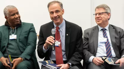 three men on panel at a talk.